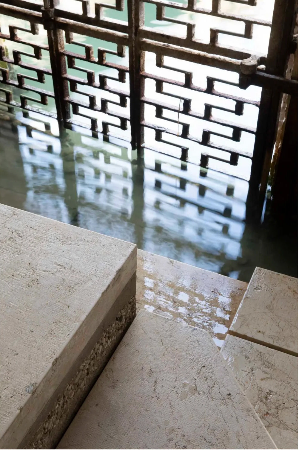 Stone steps beside water with patterned metal screen