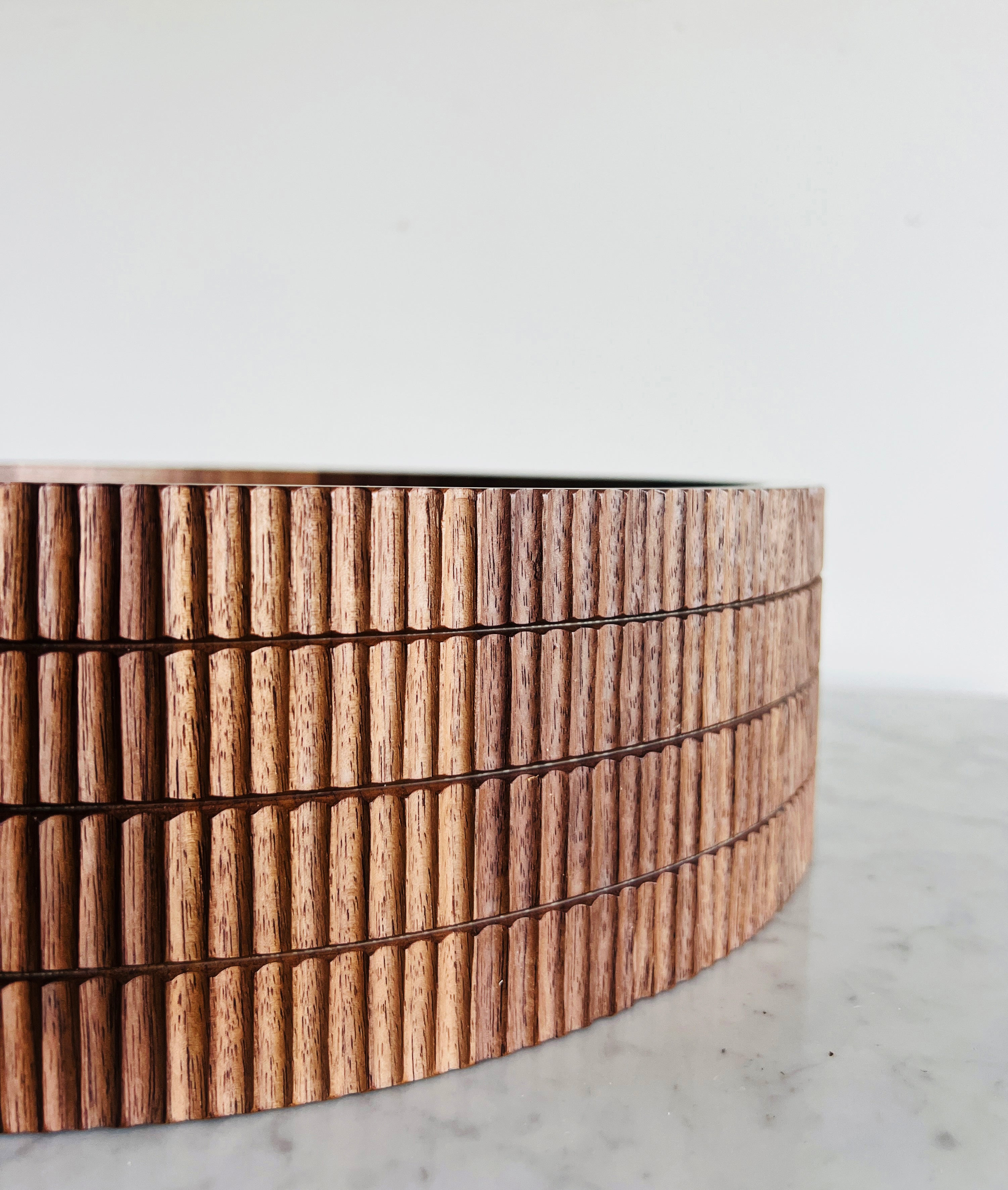 Wooden bowl with a ribbed texture on a marble surface