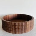 Wooden bowl with a ribbed texture on a white surface