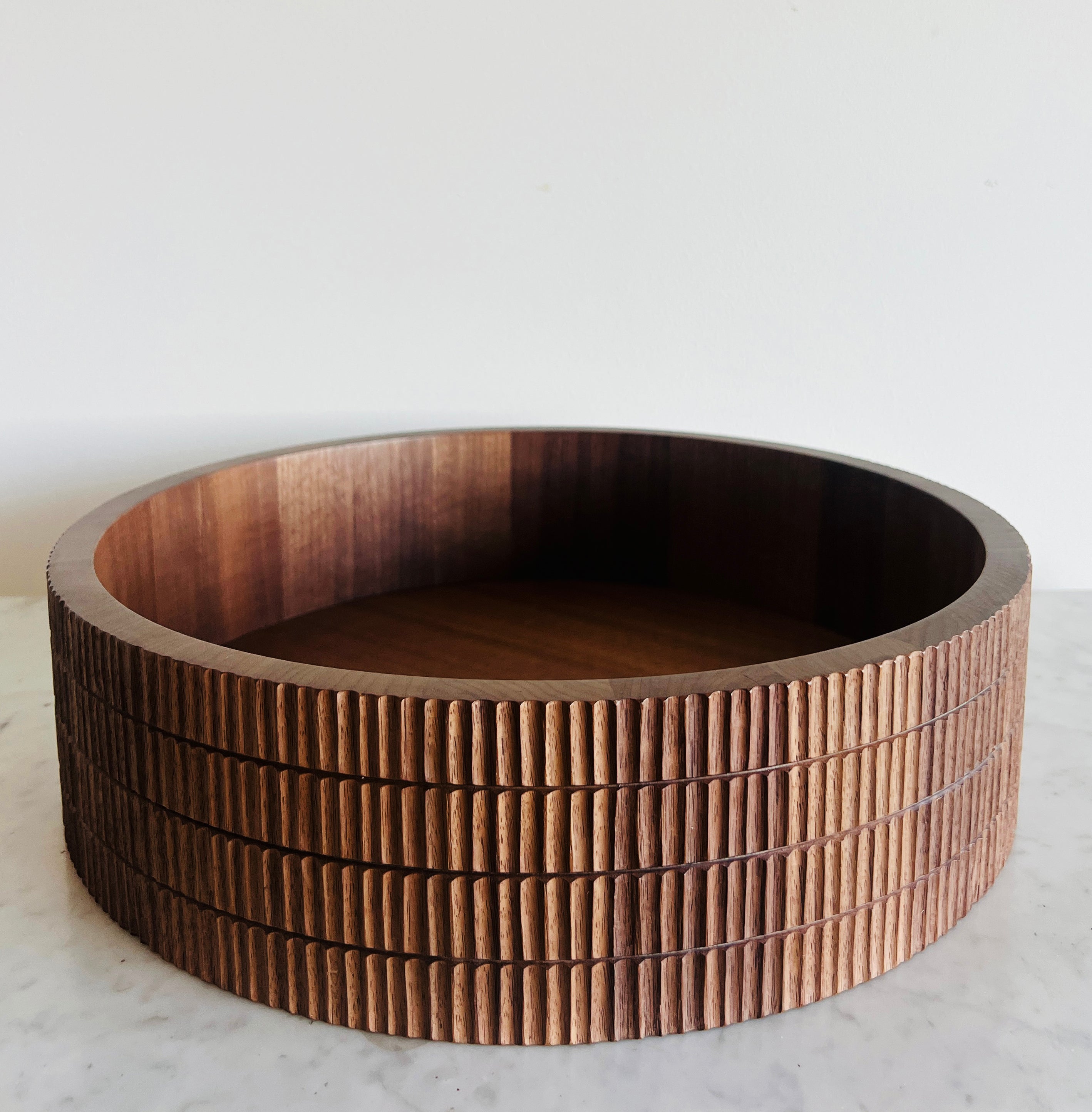Wooden bowl with a ribbed texture on a white surface